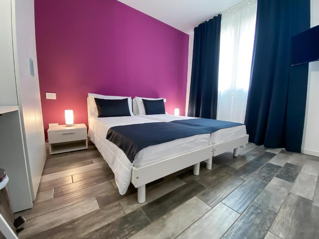 1 dormitorio con 1 cama grande y pared morada en Bonne Nuit Guest House en Azzano San Paolo