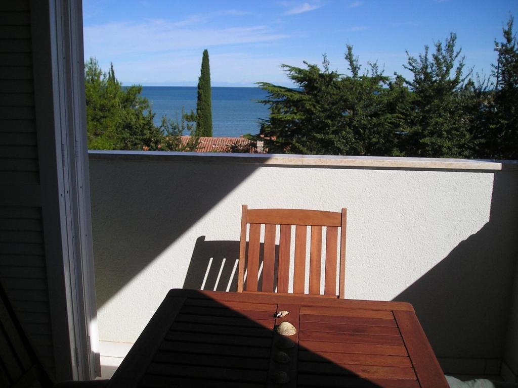 a wooden chair on a balcony with a view of the ocean at Apartments Henc in Novigrad Istria