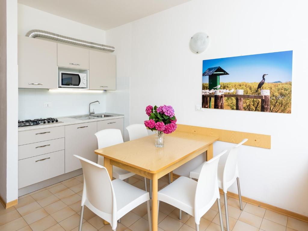 cocina y comedor con mesa de madera y sillas en Condominio Lavinia, en Bibione