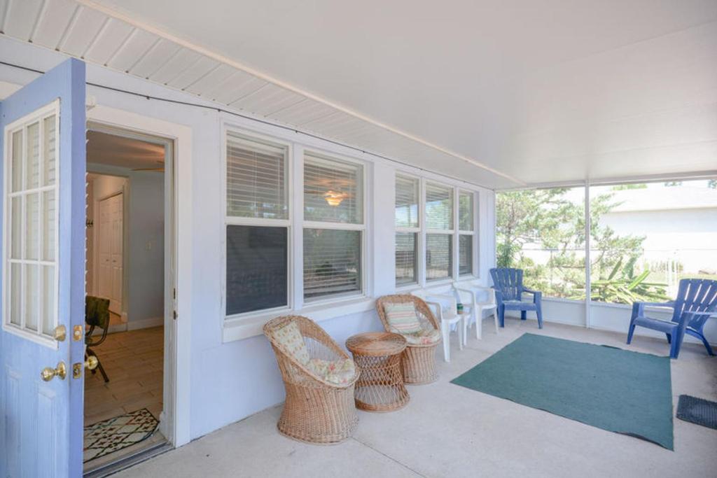 a screened in porch with chairs and a table at Charming Beachside Home by Ocean Properties in New Smyrna Beach