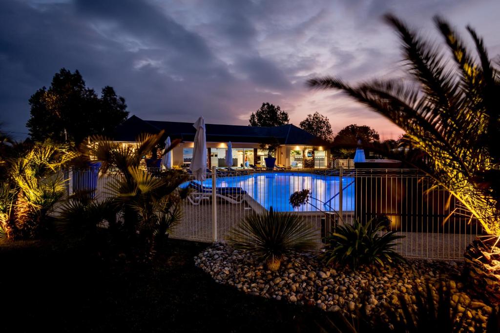 una casa con piscina por la noche en M&amp;V Resort Camping, en Langrune-sur-Mer