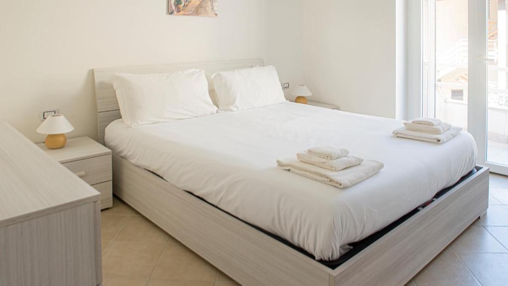 una camera da letto con un letto bianco e asciugamani di Welcomely - La Maddalena 20 ad Alghero