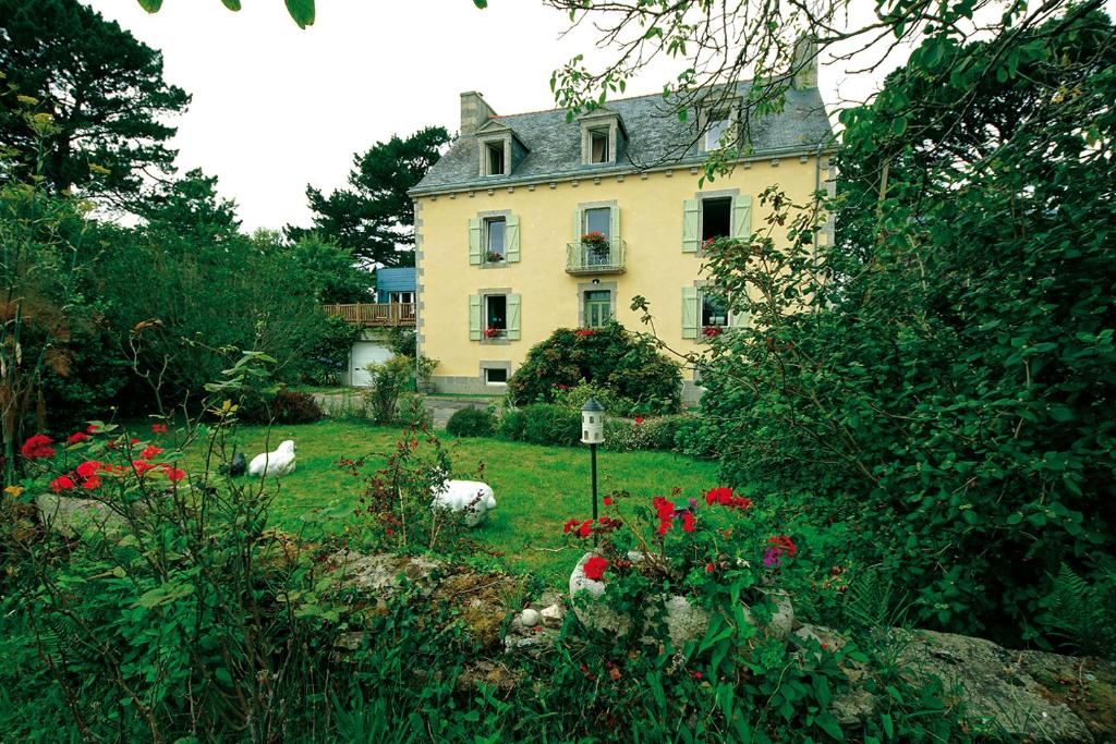 uma grande casa amarela com animais no quintal em Maison de Kersalomon em Concarneau