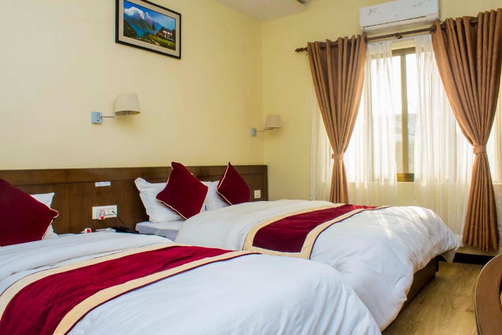 a bedroom with two beds with red and white sheets at Amarapali Cottage and Restaurant Pvt. Ltd in Butwāl