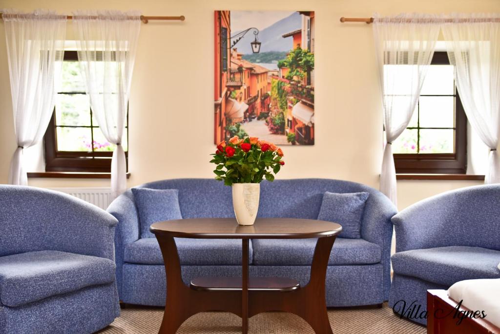 a living room with blue couches and a table with a vase of flowers at Villa Agnes Karpacz-Miłków in Karpacz