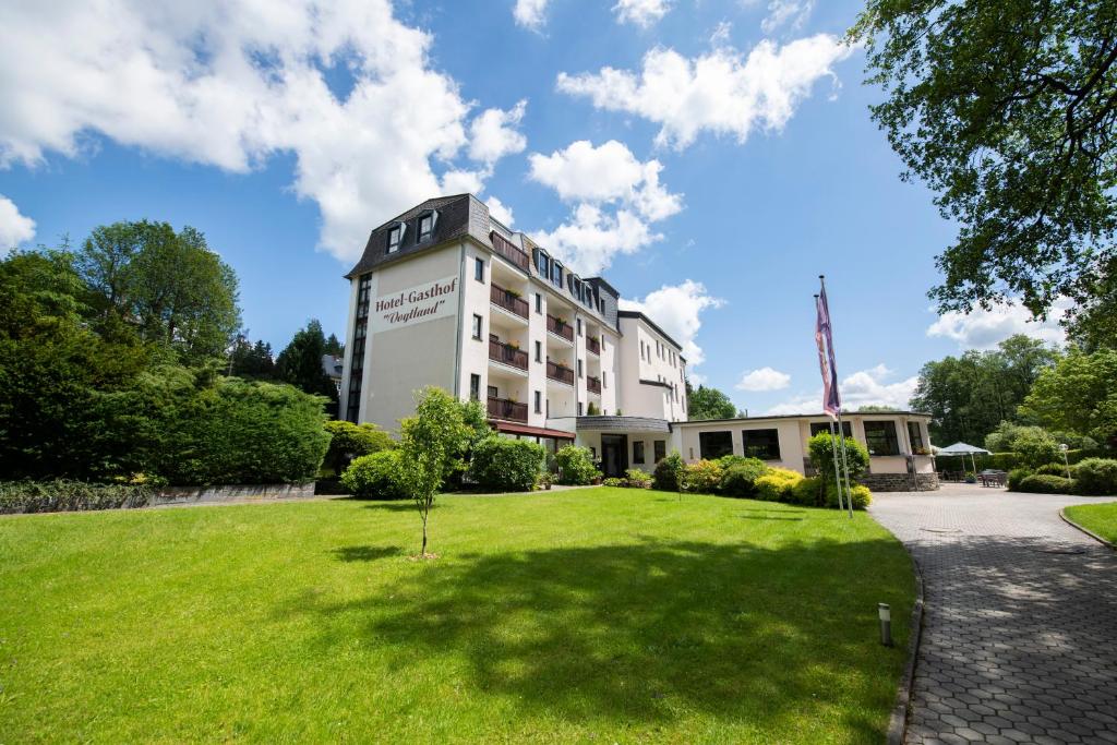 un edificio con un césped verde delante de él en Hotel Vogtland en Bad Elster