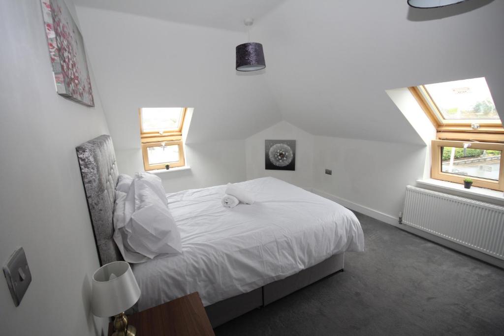 a bedroom with a white bed with two windows at Holden Court Apartment 5 in West Drayton