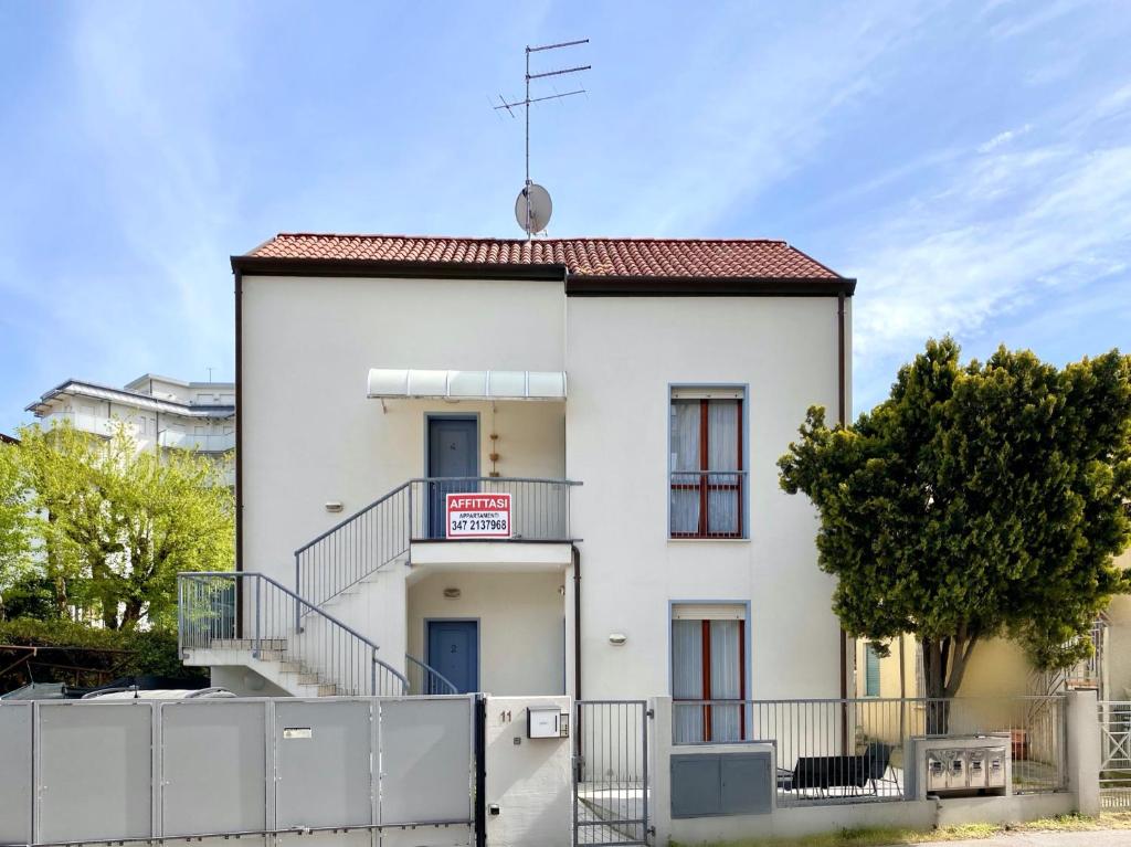 a white building with a sign on it at Villa Santin Carraro Immobiliare - Family Apartments in Lido di Jesolo