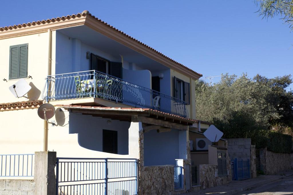 a white house with a balcony with a blue railing at Casa Isidoro in Cala Liberotto