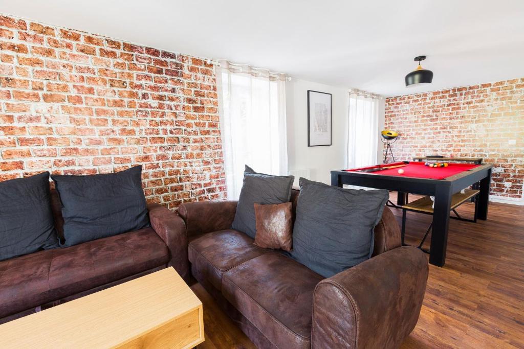 a living room with a couch and a ping pong table at Au Refuge Hyper centre Joigny in Joigny