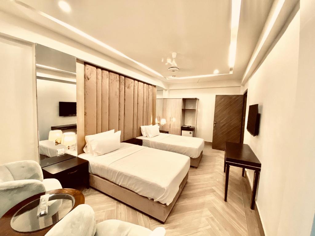 pokój hotelowy z 2 łóżkami i stołem w obiekcie Shelton's Ambassador w mieście Islamabad