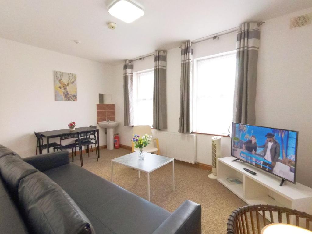 a living room with a couch and a flat screen tv at Carnation Flat A in Wembley in London