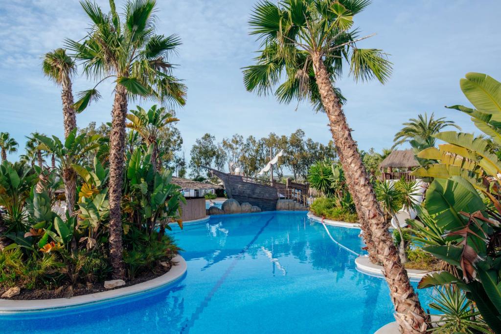 una piscina en el complejo con palmeras en Alannia Guardamar, en Guardamar del Segura