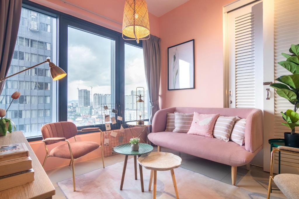 Georgetown Tropicana 218 by Airlevate Suites في جورج تاون: غرفة معيشة مع أريكة وردية ونافذة كبيرة