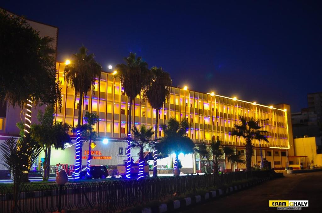 a building with palm trees in front of it at night at Jewel Matrouh Hotel in Marsa Matruh