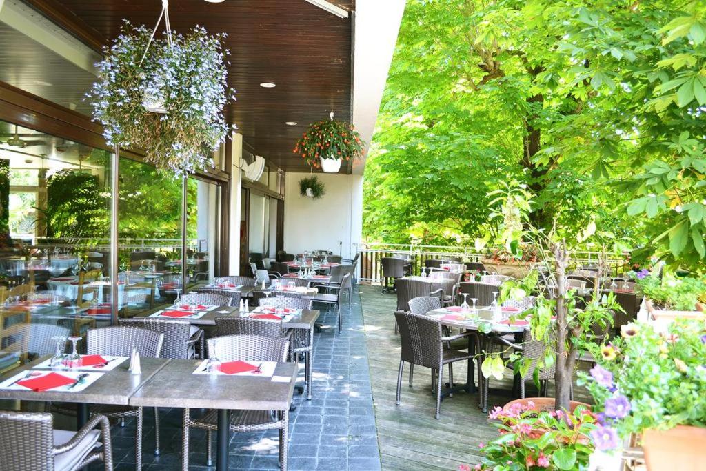 un restaurante con mesas, sillas y árboles en Hôtel la Scala, en Pithiviers