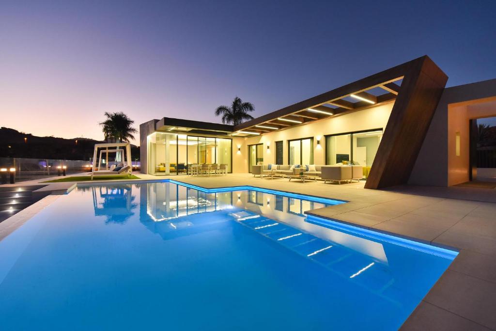 a large swimming pool in front of a house at Salobre Sunset Villa V&L Salobre by VillaGranCanaria in Maspalomas