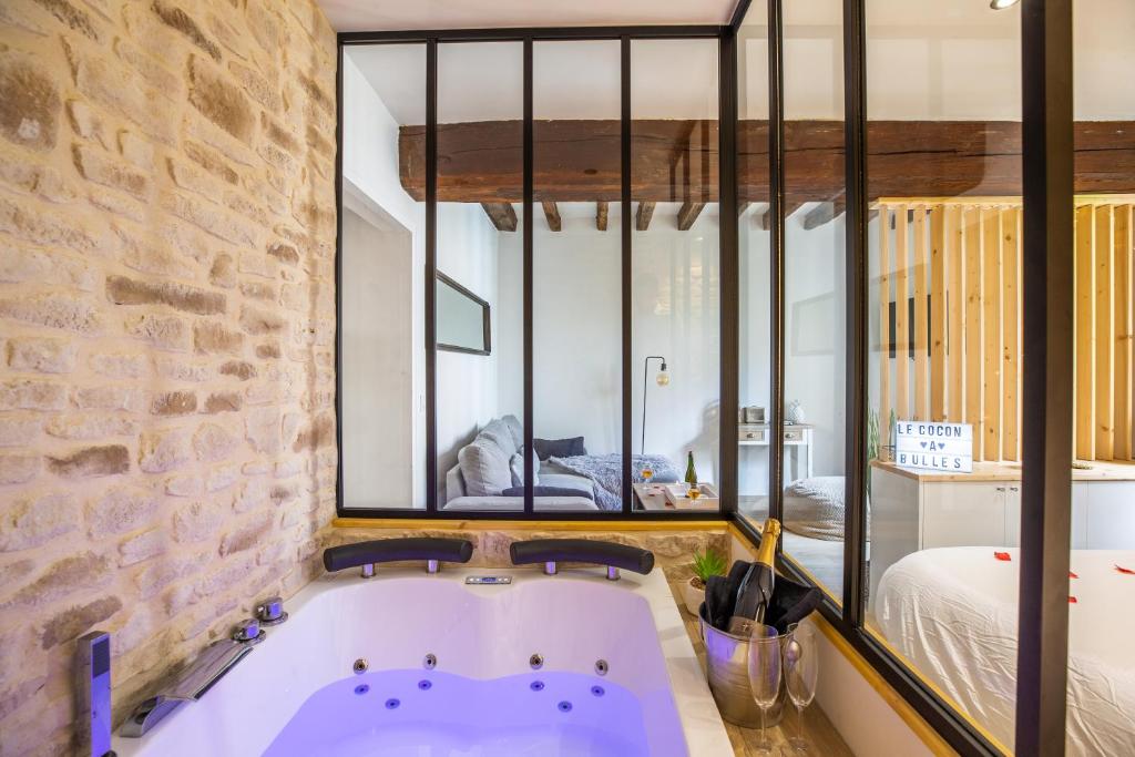 Cette chambre dispose d'une baignoire et d'un mur en briques. dans l'établissement Cocon à Bulles Chic vue Cathédrale avec Spa-jacuzzi, à Chartres