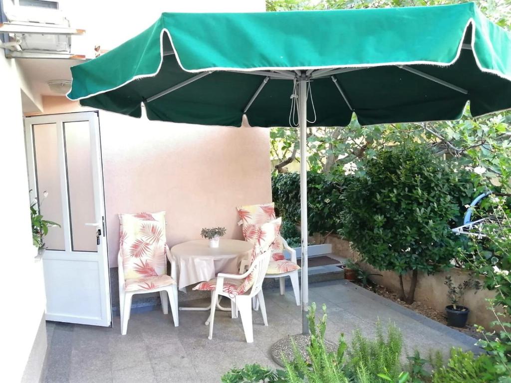 ein Tisch und Stühle unter einem Sonnenschirm auf einer Terrasse in der Unterkunft Apartman Mario in Makarska