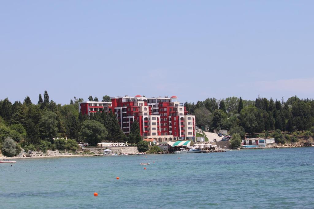 a large red building on the shore of a body of water at Rich-1 SP apartments in Ravda