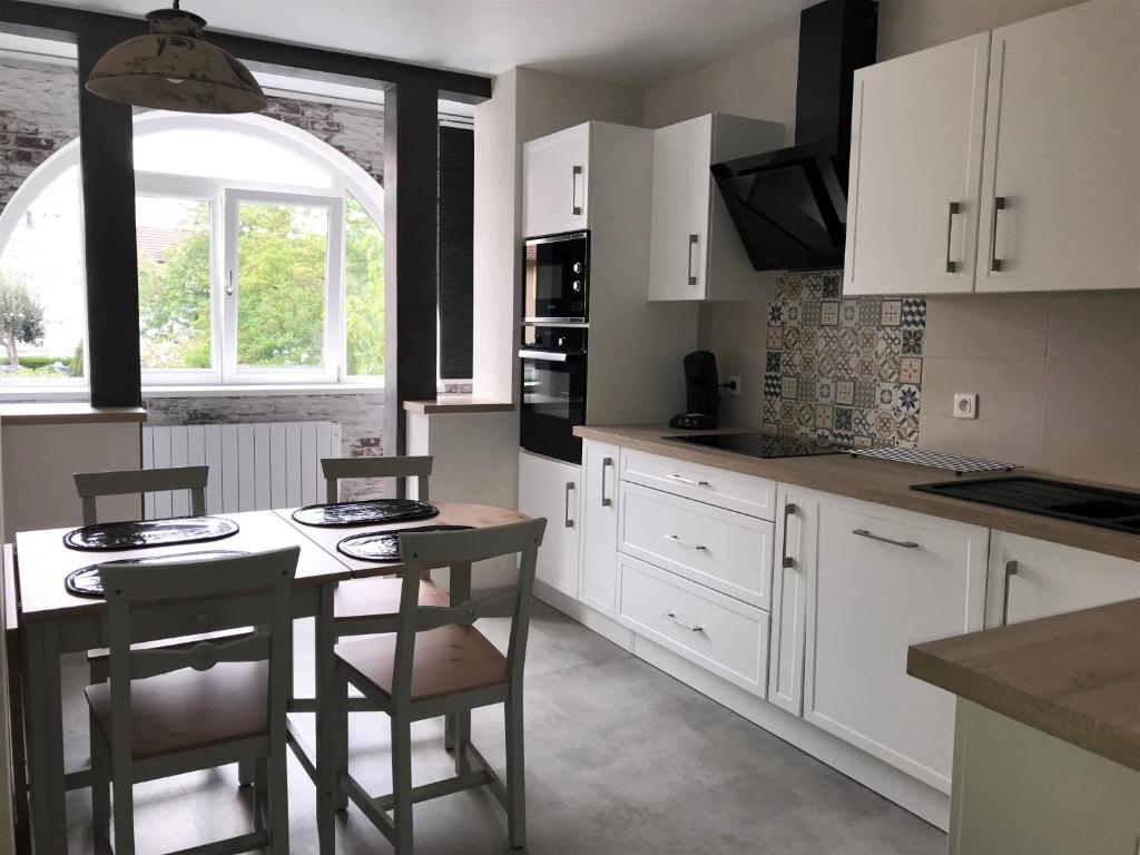 a kitchen with white cabinets and a table and chairs at Le coin de Fréderic in Colmar