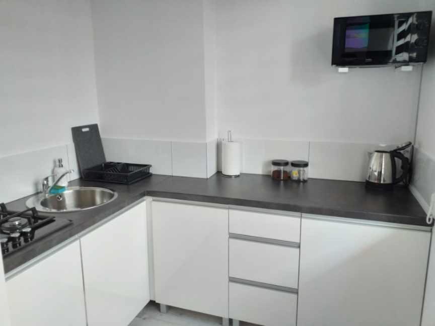 a white kitchen with a sink and a microwave at Apartamencik na Doby - Lubin in Lubin