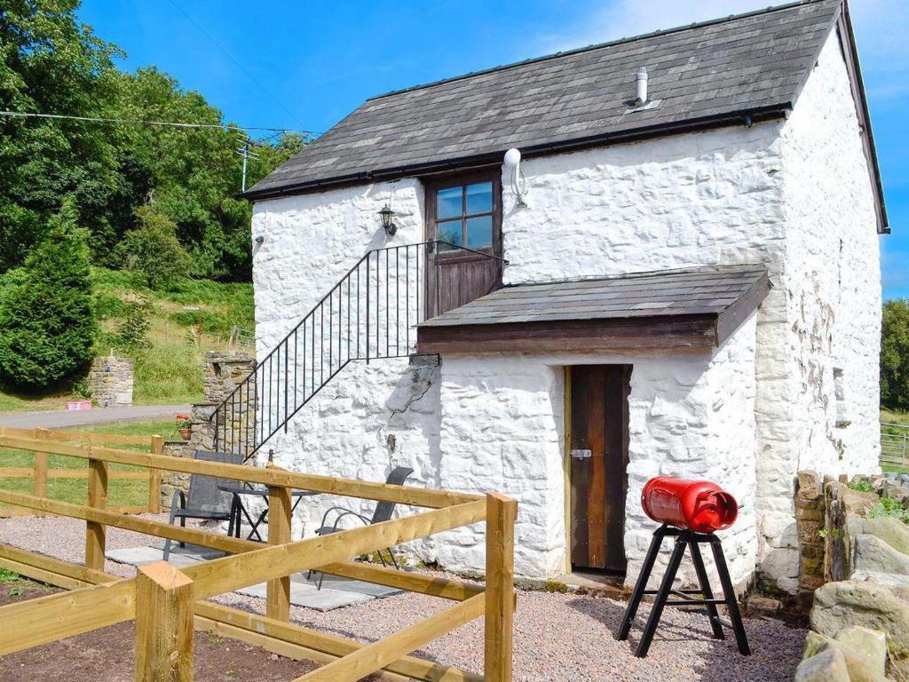 a small white stone cottage with a wooden staircase at Ty-Gwyn in Abergavenny