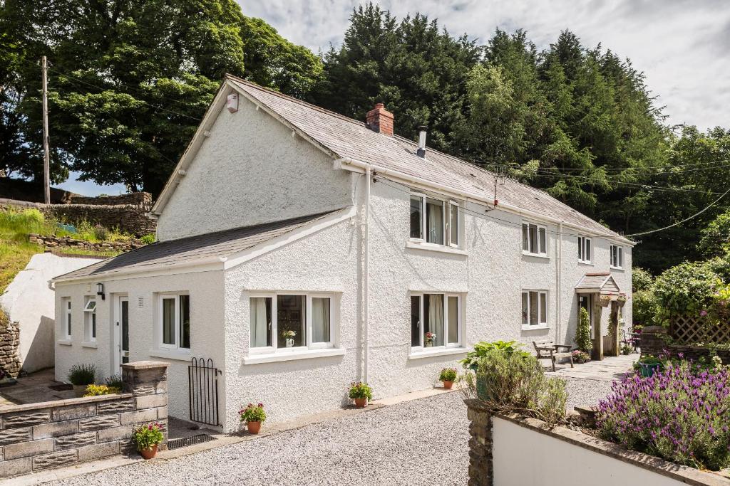 una casa blanca con flores delante en 2 Tan Yr Eglwys, en Pontardawe