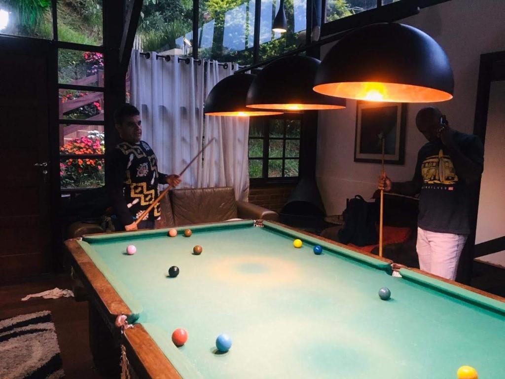 two men standing in a living room with a pool table at Casa Petrópolis Temporada in Petrópolis