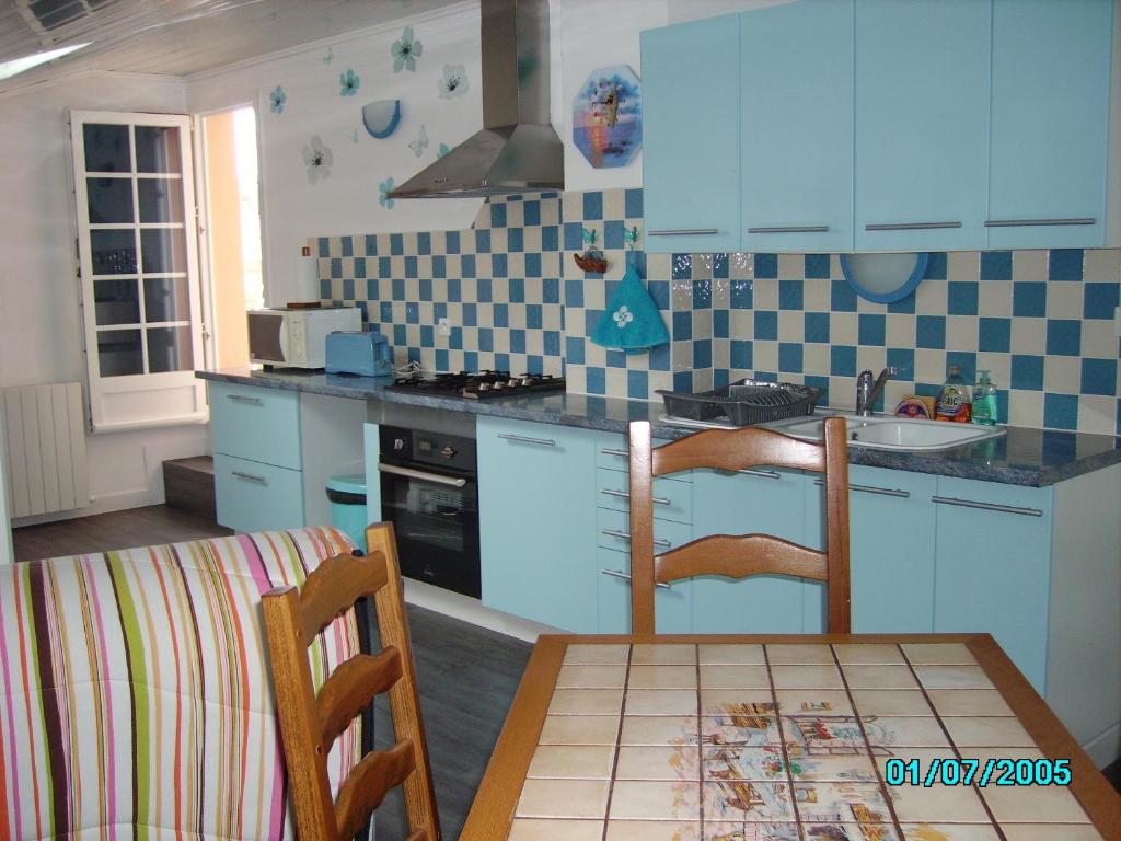 une cuisine avec des armoires bleues et une table et des chaises dans l'établissement CHEZ MARTINE Appt climatisé 1 Chambre, à Capbreton