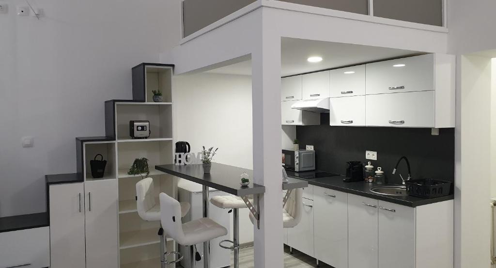 een keuken met witte kasten, een aanrecht en stoelen bij Belvárosi Apartman 2 in Miskolc