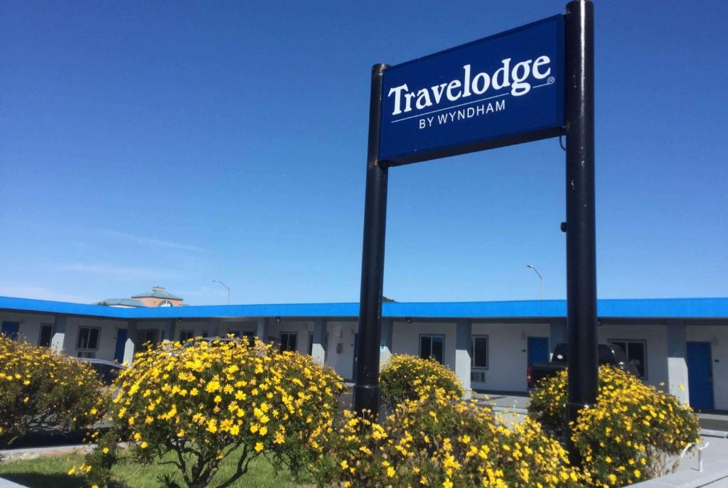 a blue sign in front of a building with yellow flowers at Travelodge by Wyndham Crescent City in Crescent City