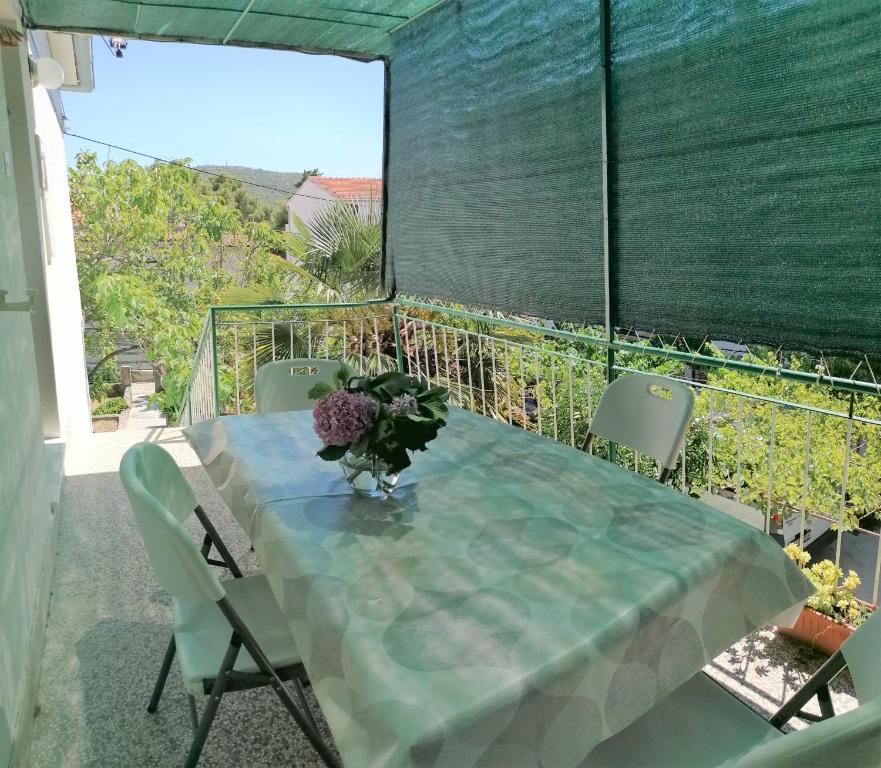 een tafel met een vaas met bloemen op een balkon bij Porat Primošten in Primošten