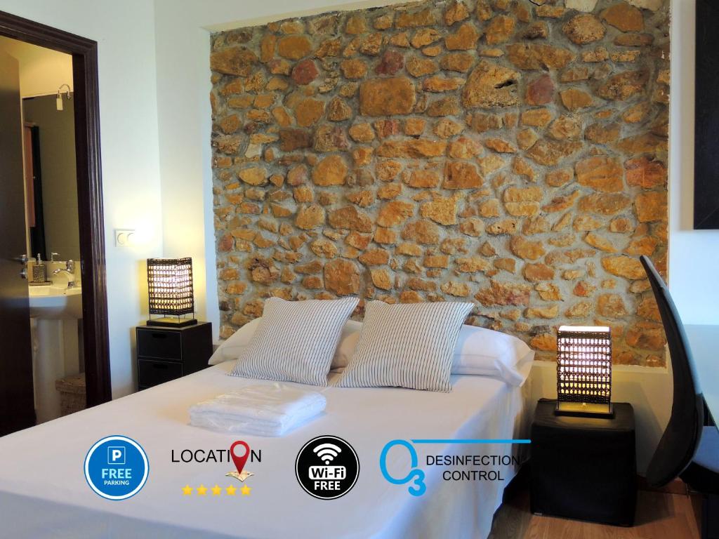 Un dormitorio con una pared de piedra y una cama en Casa Nacho by Delabra Apartments, en Oviedo