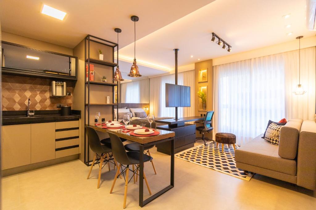 a kitchen and living room with a table and a couch at Luxuoso Apto Em Frente Ao Shopping Curitiba - Piscina, Academia e Sauna in Curitiba