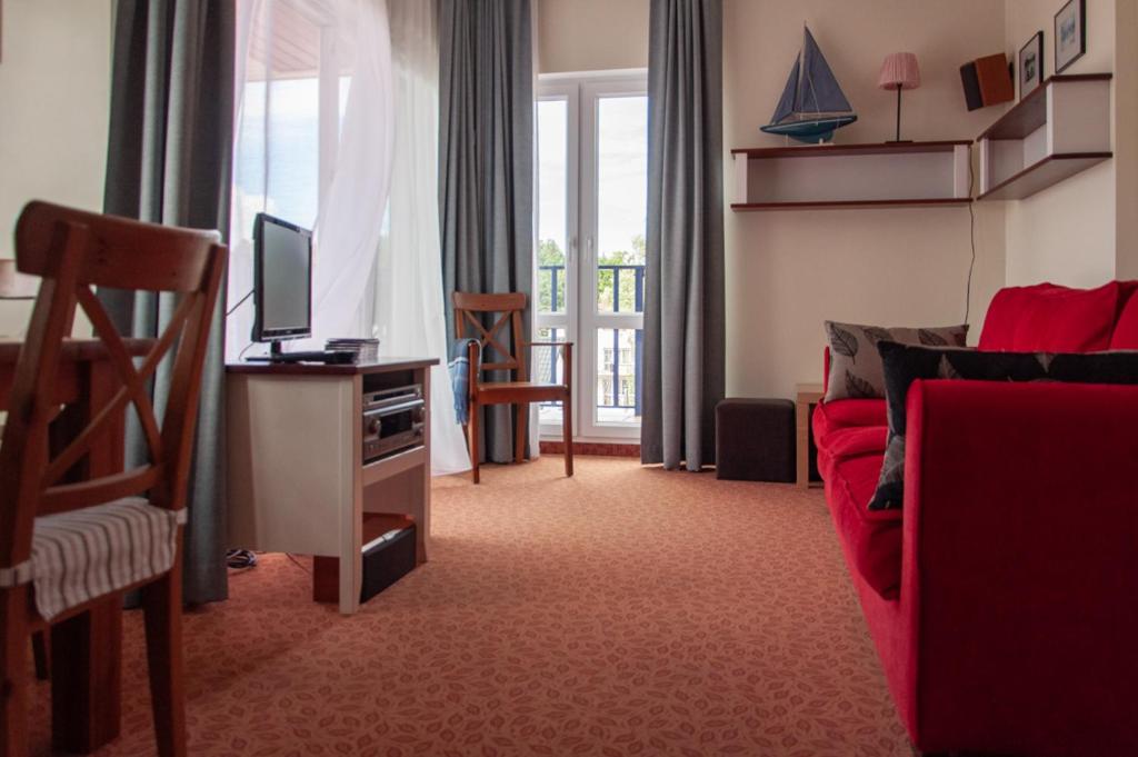 Villa Baltic 14 Chałupy في شالوبي: غرفة معيشة بها أريكة حمراء وتلفزيون
