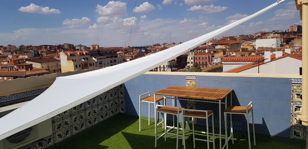 un balcone con 2 sgabelli e un tavolo su un edificio di Apartamentos La Muralla a Zamora