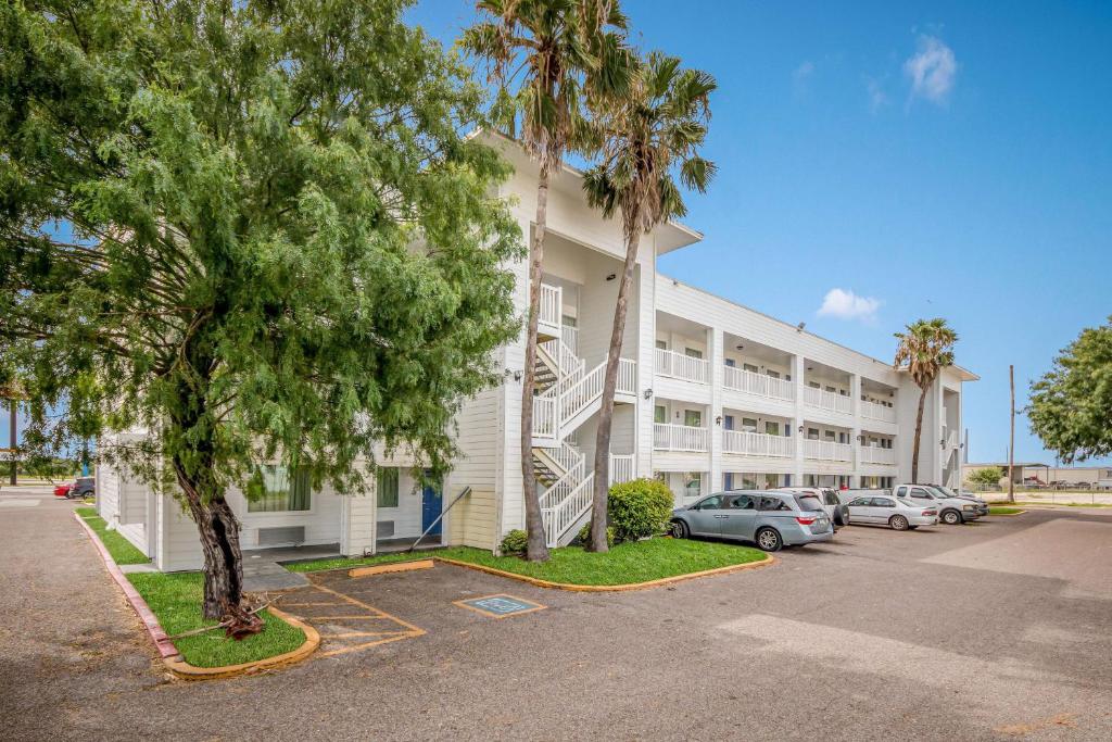 un grand bâtiment blanc avec des voitures garées dans un parking dans l'établissement Motel 6-Corpus Christi, TX, à Corpus Christi