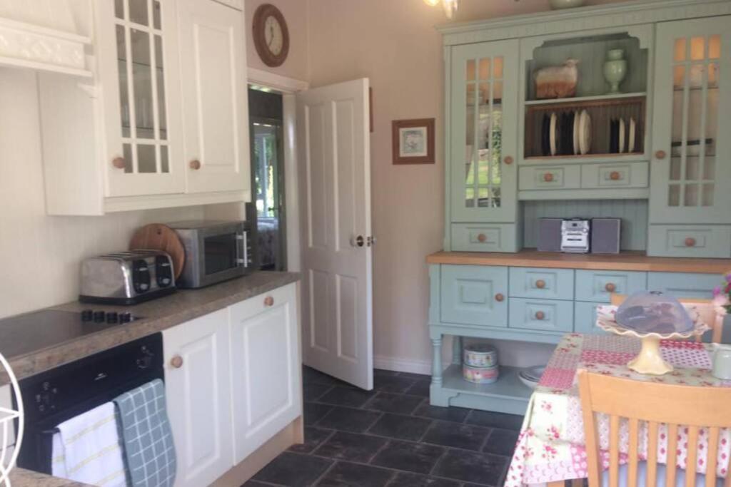 una cocina con armarios azules y blancos y una mesa. en Rhubarb Cottage, en Enniskillen