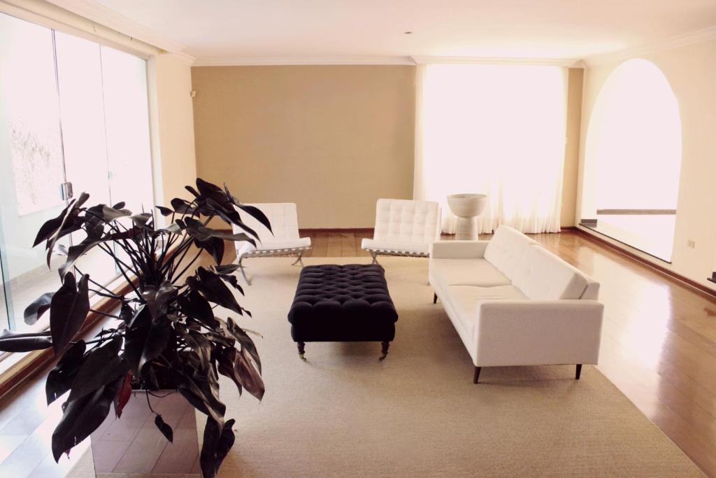 a living room with white furniture and a potted plant at Mansão Morumbi 91 in São Paulo