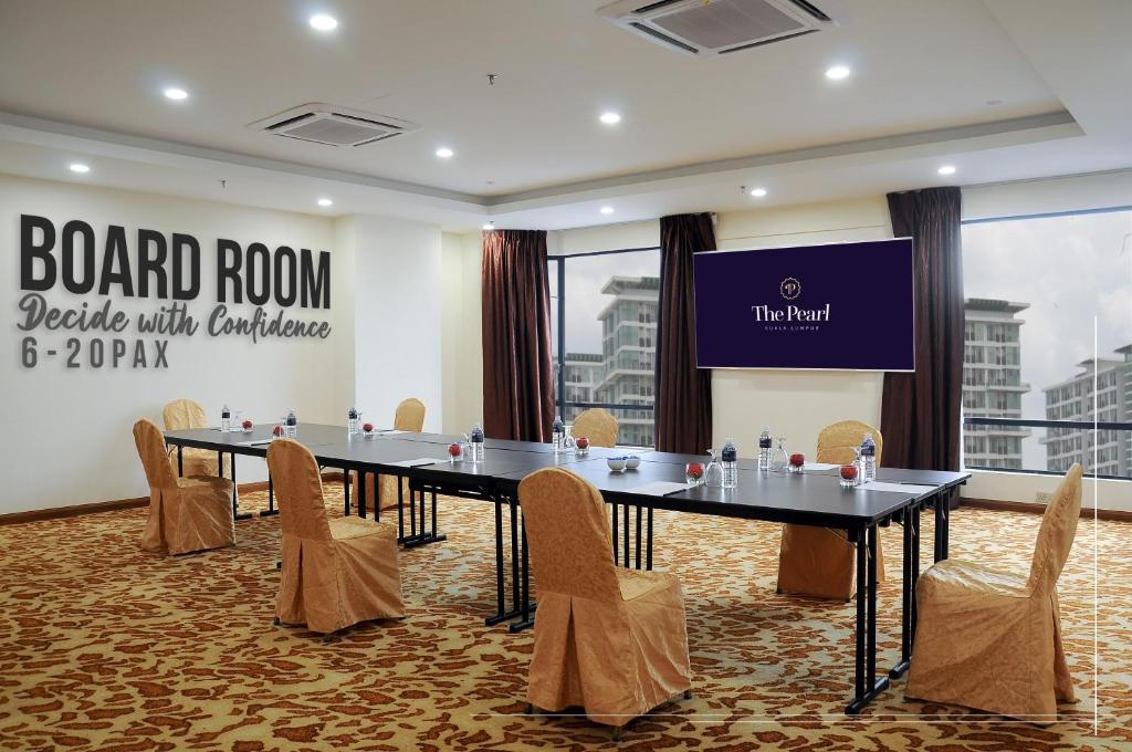A boardroom set for meetings, with a presentation screen, windows, and seating for a small group.