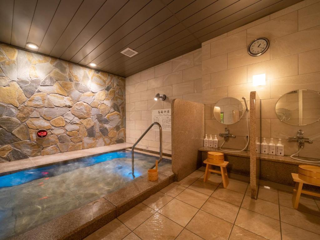 a bathroom with a tub and a sink and a tub at Super Hotel Iyo Saijo in Saijo