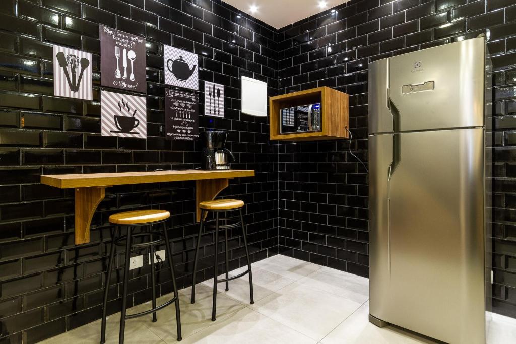 uma cozinha com frigorífico e um bar com azulejos pretos em Le Chalet Boutique em Campos do Jordão