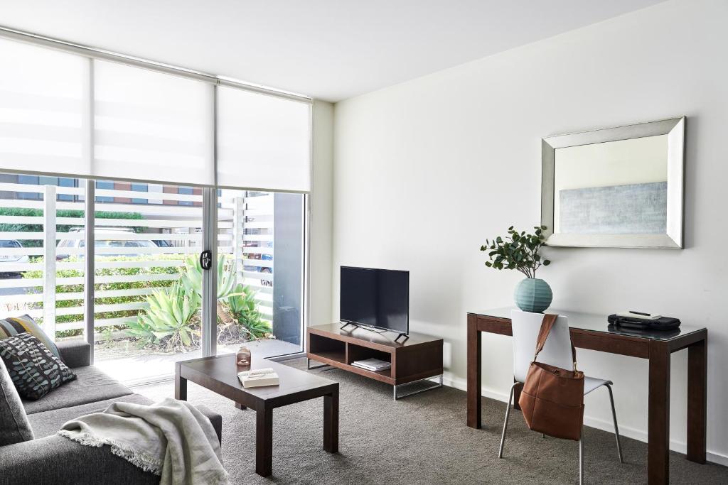 a living room with a couch and a tv at Punthill Knox in Wantirna South