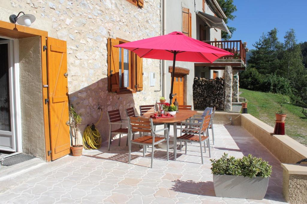 een tafel en stoelen met een rode parasol op een patio bij L'Oustal de l'Annetta Chambres et Tables d'Hôtes in Comus