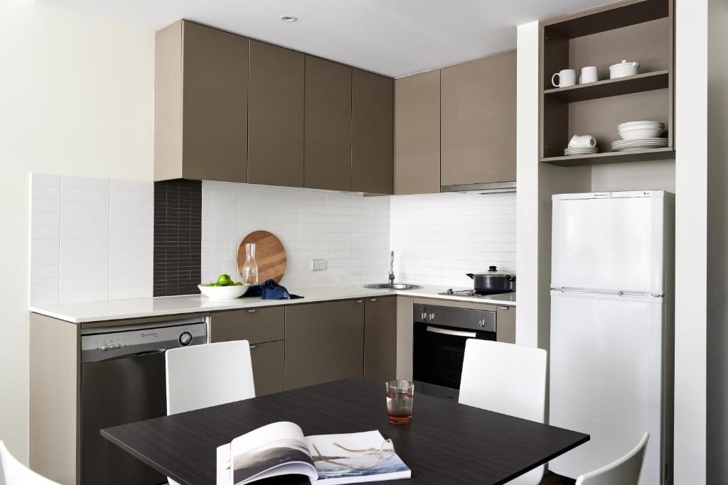 a kitchen with a black table and white appliances at Punthill Knox in Wantirna South