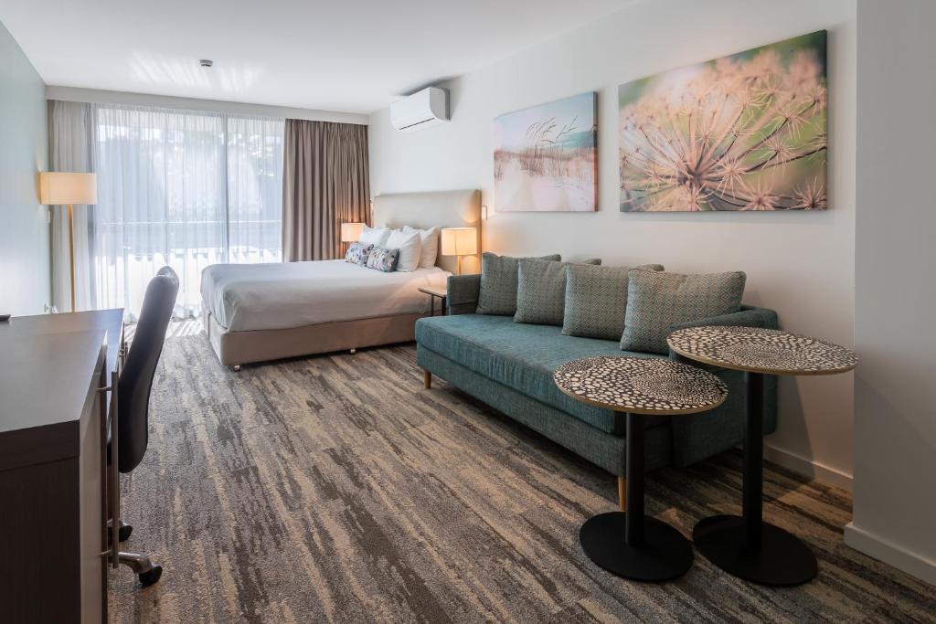 a hotel room with a couch and a bed at Narrabeen Sands Hotel by Nightcap Plus in Narrabeen