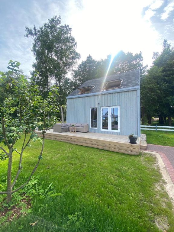 a small blue house in a yard with a green lawn at 2 bedroom house Ragakrasts in Mērsrags