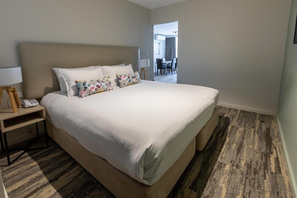 a bedroom with a large white bed with pillows at Narrabeen Sands Hotel by Nightcap Plus in Narrabeen
