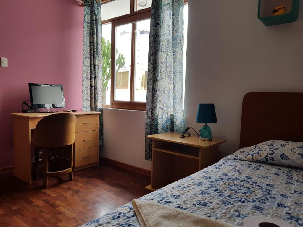 een slaapkamer met een bed, een bureau en een raam bij EL ENSUEÑO in Lima